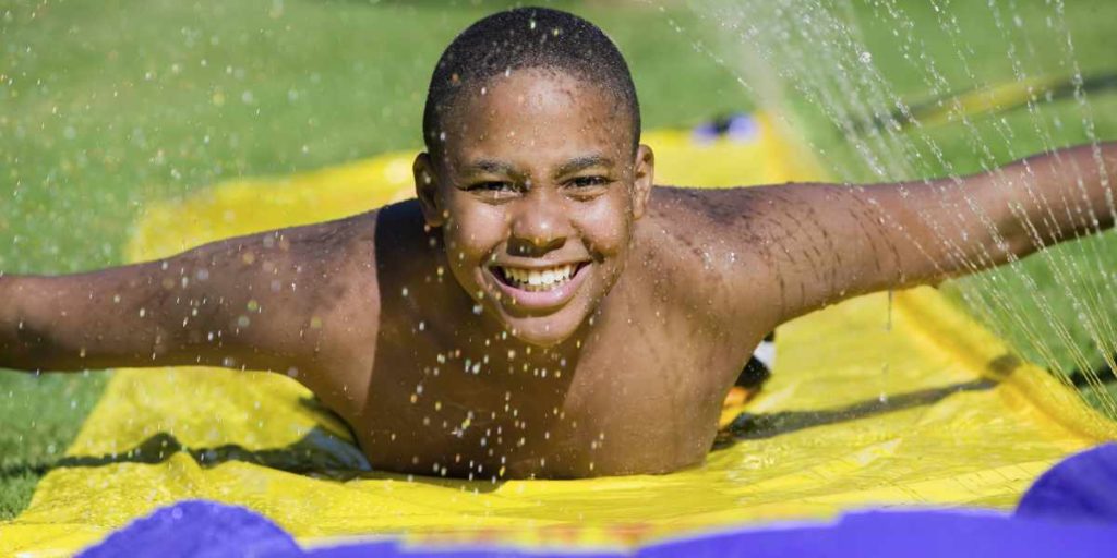 Kinder haben mit einer Wasserrutschbahn viel Freude